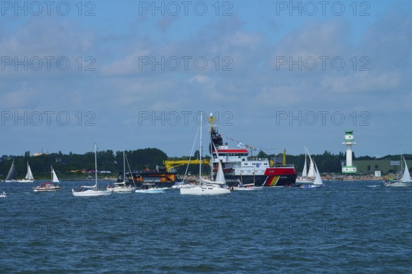Large ship Arkona Coast Guard and numerous smaller sailing boats in the water in front of a