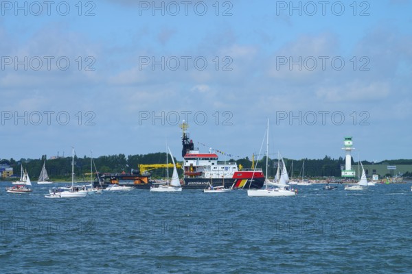 Various boats and a large ship Arkona Coast Guard on the sea next to a lighthouse Friedrichsort,