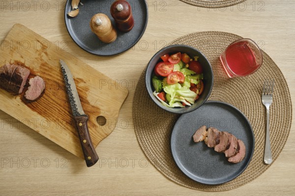 Slices of succulent duck breast are laid out on a cutting board beside a vibrant salad filled with