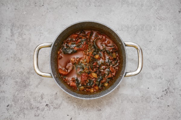 A large pot filled with a flavourful beef and vegetable stew on a gray kitchen countertop.