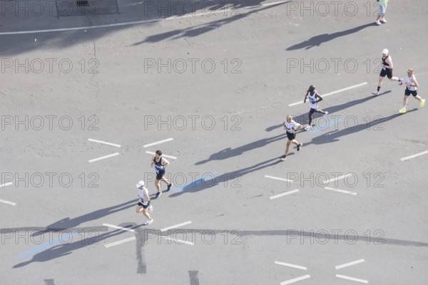 Runners with long shadows on the big star seen from the Victory Column at the 51st BMW Berlin