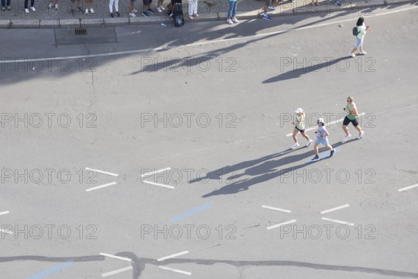 Runners with long shadows on the big star seen from the Victory Column at the 51st BMW Berlin
