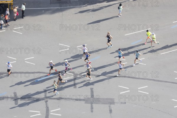 Runners with long shadows on the big star seen from the Victory Column at the 51st BMW Berlin