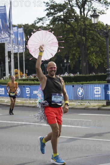 A runner with an umbrella on the Großer Stern at the 51st BMW Berlin Marathon 2025 on 21 September
