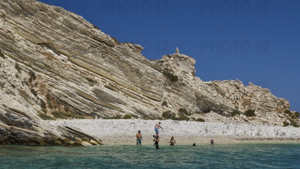 Group of people swimming in clear water in front of rocky beach landscape, White Cliffs, White