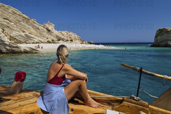 Woman sitting on a boat looking at the calm, turquoise-coloured seascape, White Cliffs, White