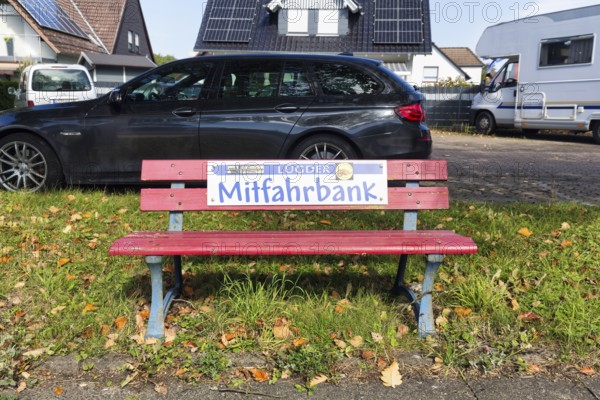 Red bench at the roadside, sign with inscription Mitfahrbank, Mitfahrerbank, symbol photo, carpool,
