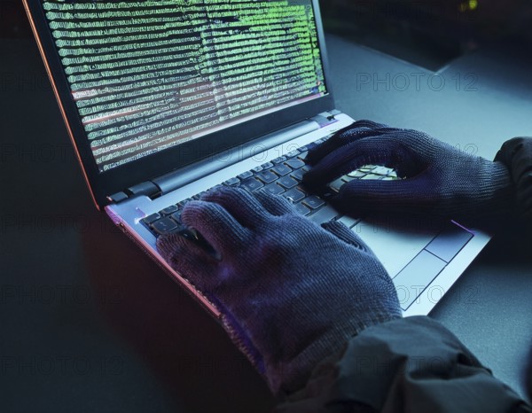 Cybersecurity threat depicted by gloved hands operating a computer, commands displayed on the