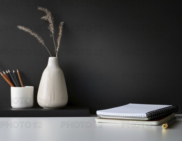 A clean and modern office workspace featuring a pen holder, notebook, and ceramic vase against a