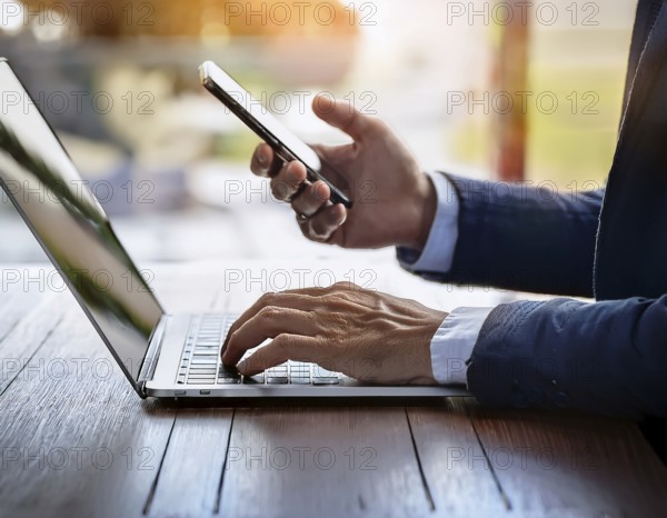 A man in a professional office environment multitasking with a smartphone and laptop, conveying