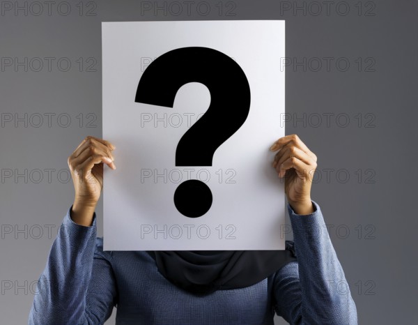 A person concealing their face while holding a question mark sign, symbolizing anonymity, mystery,