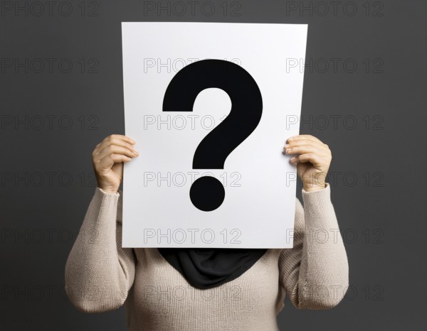 A person concealing their face while holding a question mark sign, symbolizing anonymity, mystery,