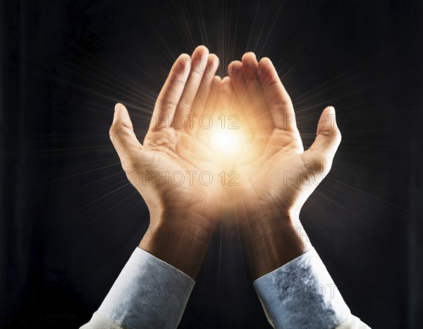 Hand holding light ray in the darkness, hope concept. Light in hands. Freedom and spirituality