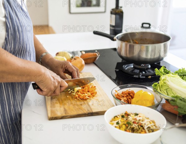 A cozy kitchen scene showing only hands of a couple preparing food, chopping vegetables, and