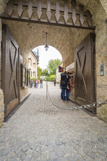 People pass a large wooden stone gate leading to a castle, Lichtenstein Castle, Lichtenstein,