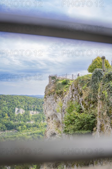 Spectacular cliff view with green landscape and wide sky in the background, captured from a railing