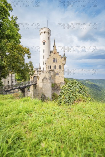 Medieval castle on a grassy cliff, surrounded by a picturesque landscape and dramatic sky,