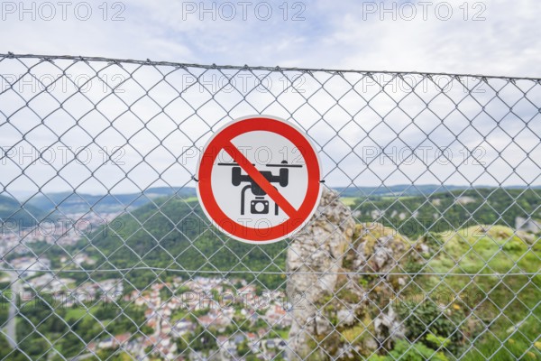 Lattice fence with drone prohibition sign in front of a wide panoramic view over the landscape,