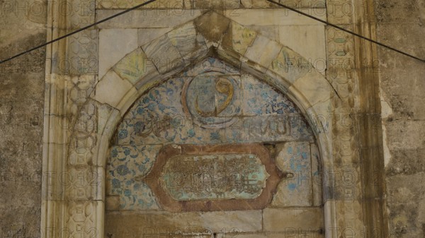 Decorated arch with faded inscriptions and ornaments on a stone background, Recep Pasha Mosque, Old
