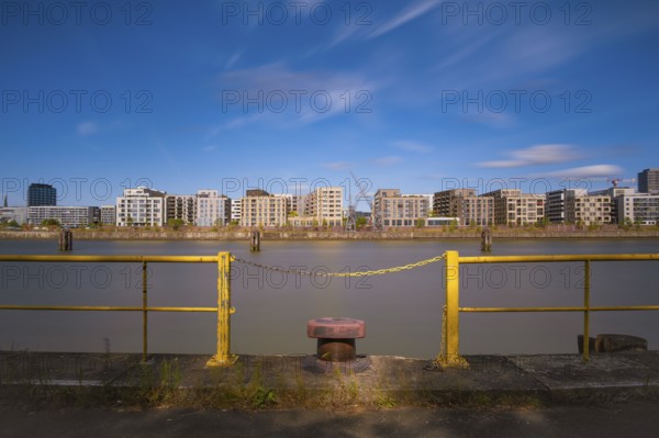 View over a harbour basin to a part of the Hamburg Hafencity in the foreground a yellow railing