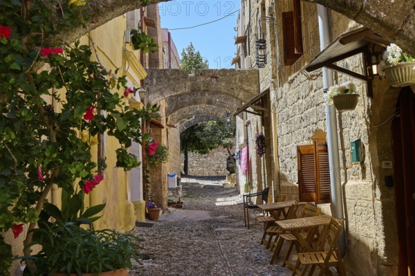 Idyllic, flower-filled alleyway with arches and old stone buildings in historic style, Turkish