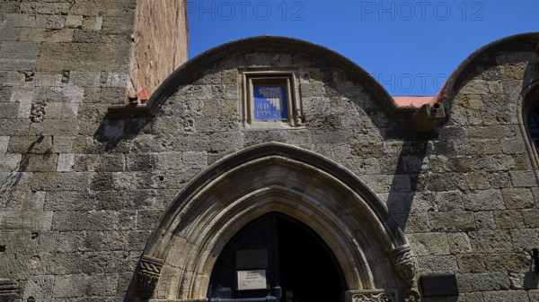 Kasteliani Public Library, Italian coat of arms, Historic stone gate under a clear blue sky, Rhodes