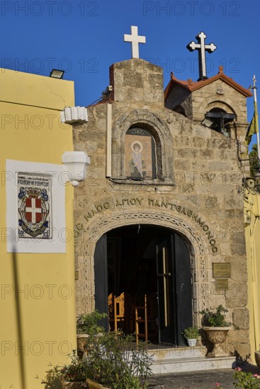 Church of Agios PanteleimoChurch entrance with icon painting and crosses, yellow wall in the
