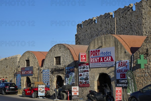 Outside the fortress walls, warehouses, row of buildings with car hire signs under historic stone