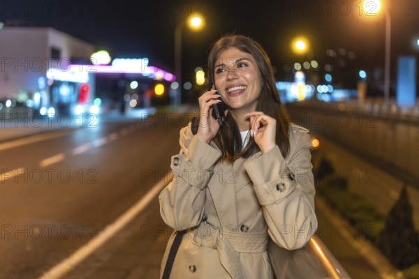 Young woman smiling and communicating on a smartphone, walking along a vibrant urban street during