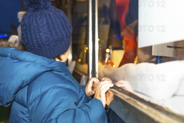 Curious child admiring a festive christmas window display in bayonne, france, during the magical