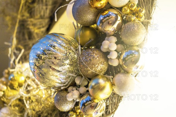 Close up of a christmas wreath with gold and silver shiny ornaments and white berries, adding a