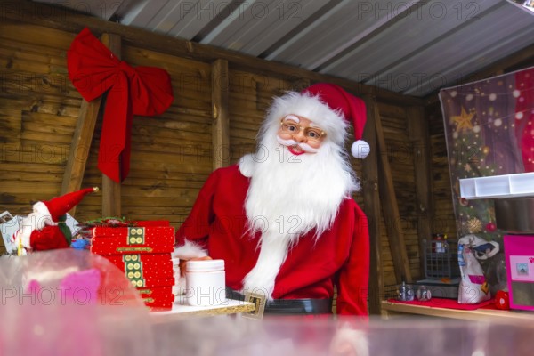 Santa claus impersonator preparing christmas gifts in a wooden kiosk at a christmas market in