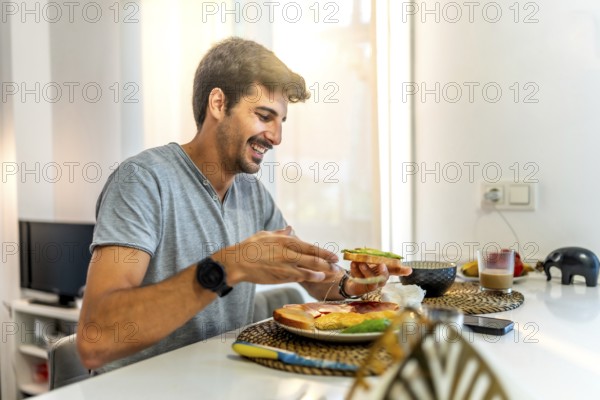Young man smiling while enjoying a nutritious breakfast of avocado toast in a stylish, modern