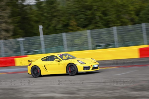 Yellow racing car sports car Porsche Cayman GT4 races at high speed top speed during trackday on