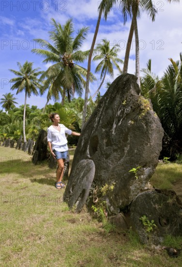 Tourist standing next to oversized huge stone coins real currency in stone money bank stone money
