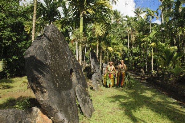 Native couple from Yap in traditional traditional costume walking on path through palm forest