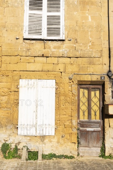 Closed door and white wooden window, historic house façade, yellow sandstone, Marville, Renaissance