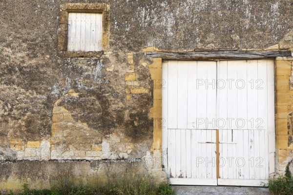 Closed white wooden door and windows, historic house façade, yellow sandstone, Marville,