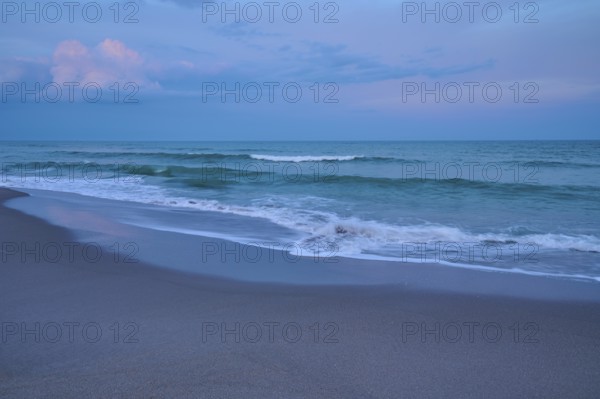 Tranquil beach landscape at dusk with gentle waves and blue sky, Cocoa Beach, Port Canaveral,