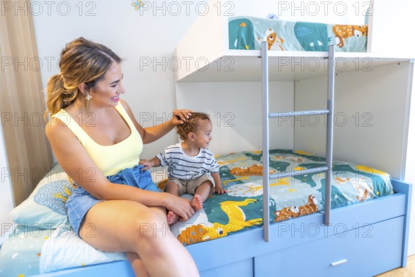Mom gently caressing her little son while sitting together on a bunk bed in a brightly colored