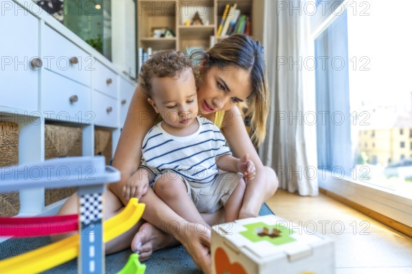 Mom and her son are sitting on the floor enjoying playtime with colorful educational toys,