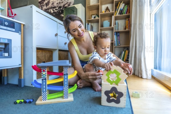 Happy mother and her cute son are playing together with colorful educational toys in a modern