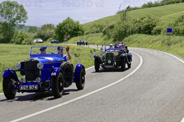 Two blue classic cars driving one behind the other on a winding country road, classic car, car