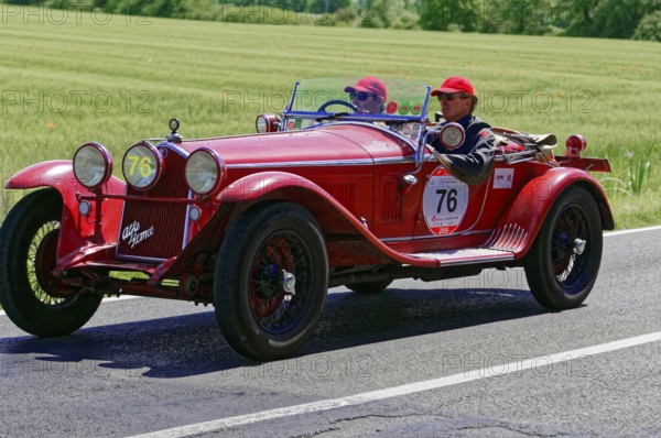 A classic red vintage car with two drivers on a country road, vintage car, car race, Mille Miglia,