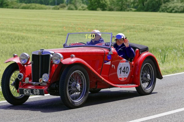 A red classic roadster drives along a rural road in fine weather, classic car, car race, Mille