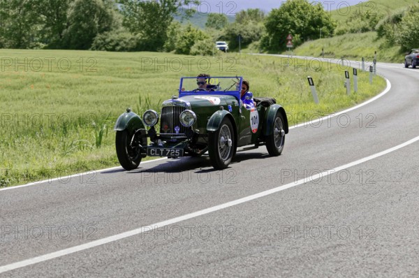 Green classic car drives on a winding country road through a green landscape, classic car, car