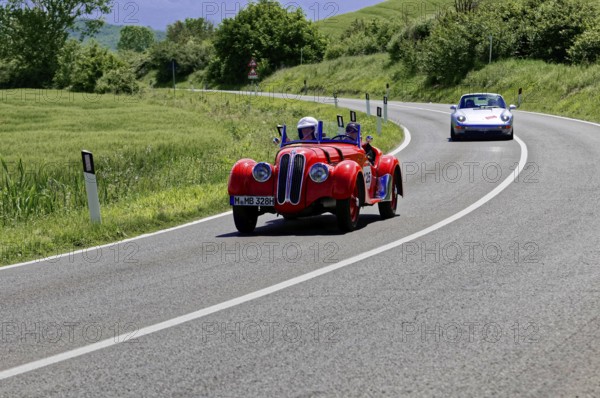 A sporty red vintage car followed by a modern vehicle on a road, vintage car, car race, Mille