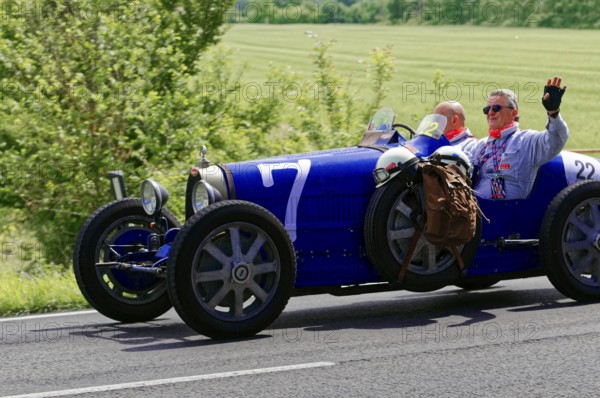 Blue classic car with two men on a country road under a sunny sky, classic car, car race, Mille