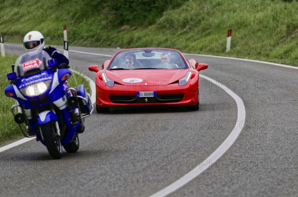 Blue motorbike overtakes red Ferrari convertible on winding road, classic car, car race, Mille