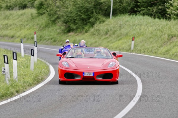 Red Ferrari convertible on winding road surrounded by green landscape, classic car, car race, Mille